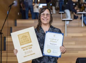 A photograph of Nana Joes Granola founder Michelle Pusateri holding her Manufacturer of the Year award and smiling.